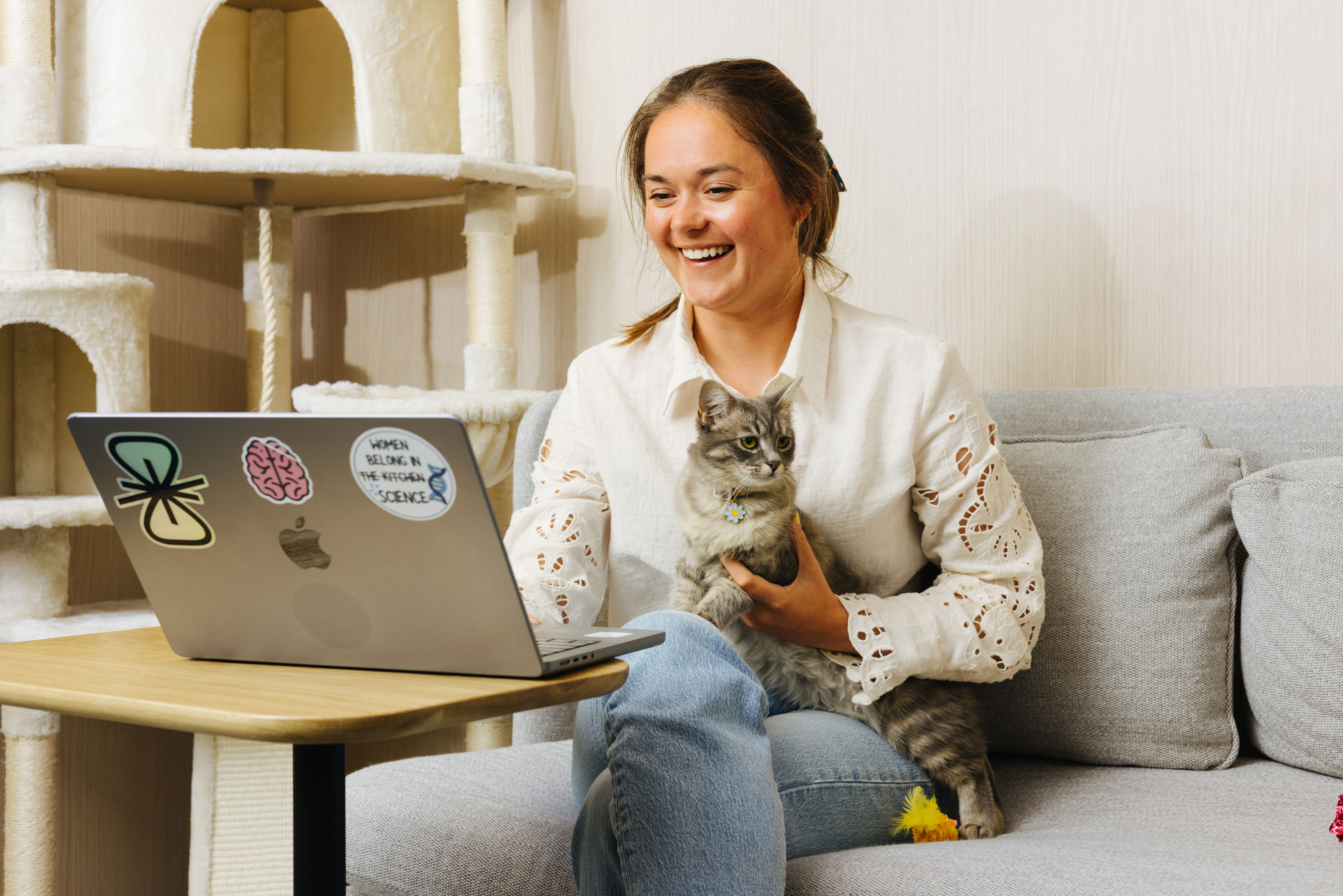 A neuroscientist works on her laptop while holding her cat in her lap. The cat's name is Marie.