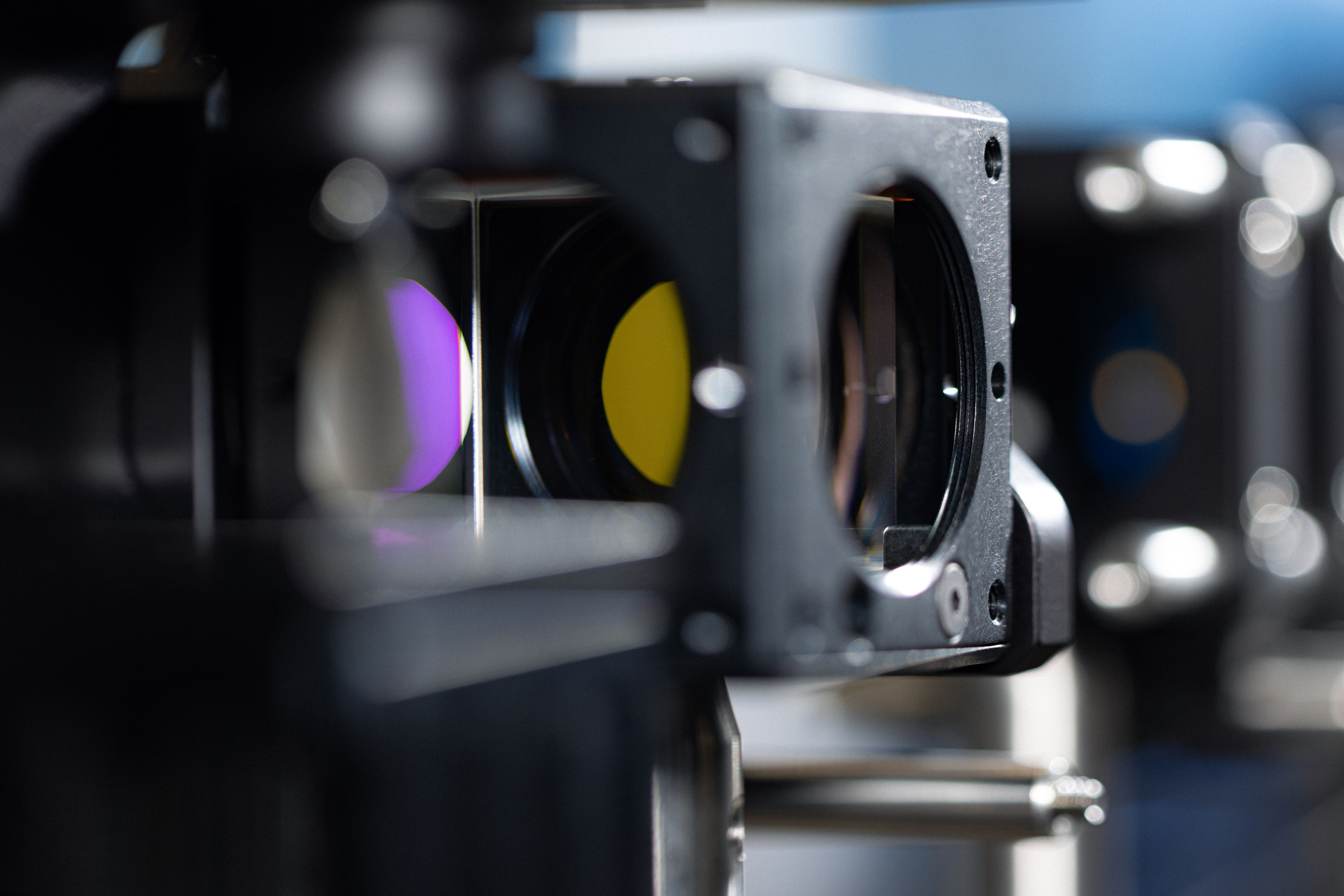 Lenses and mirrors in a lab setting photographed with shallow depth of field.