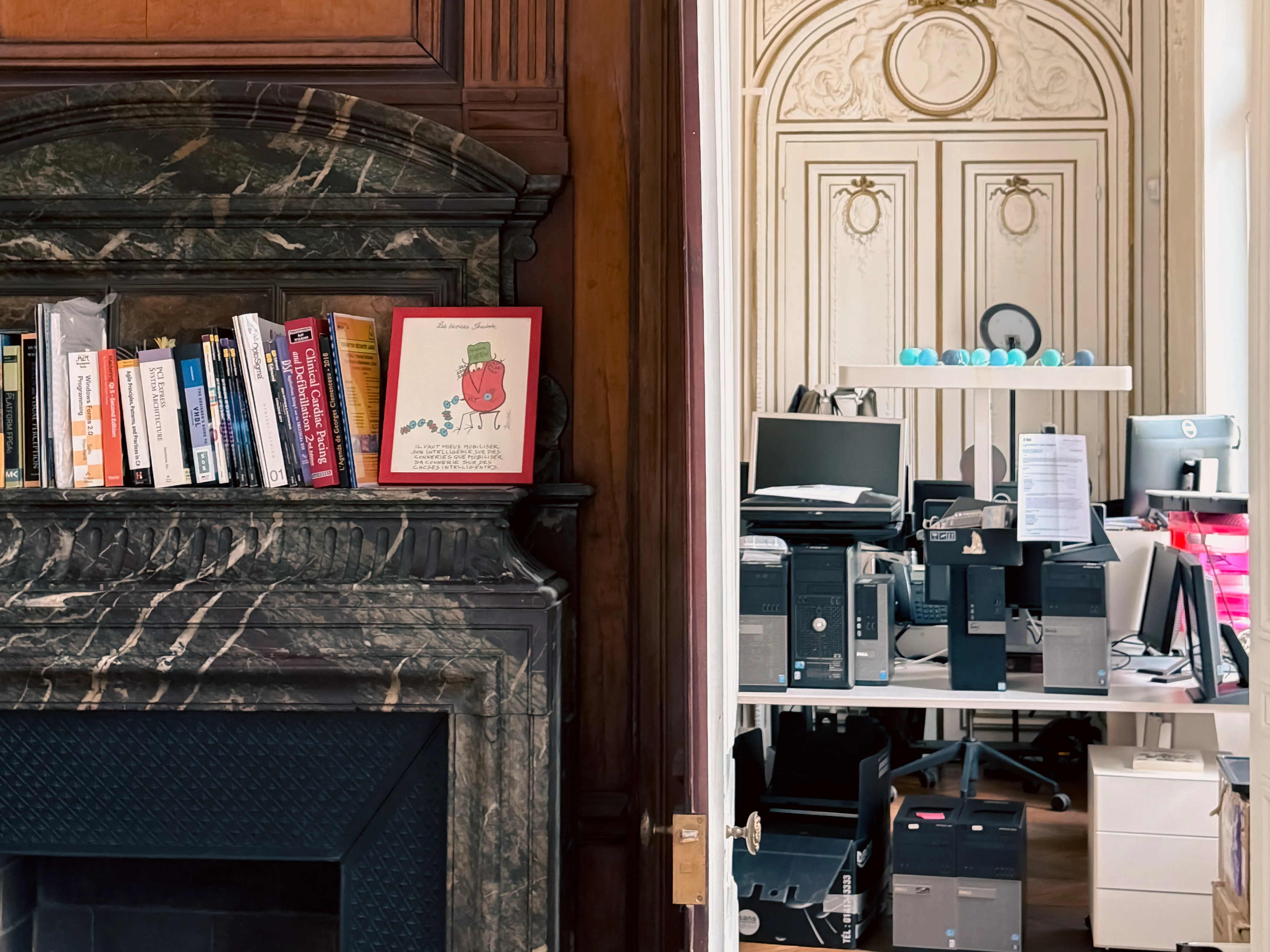 Photo of books on the mantle of a fireplace in the Paris office.