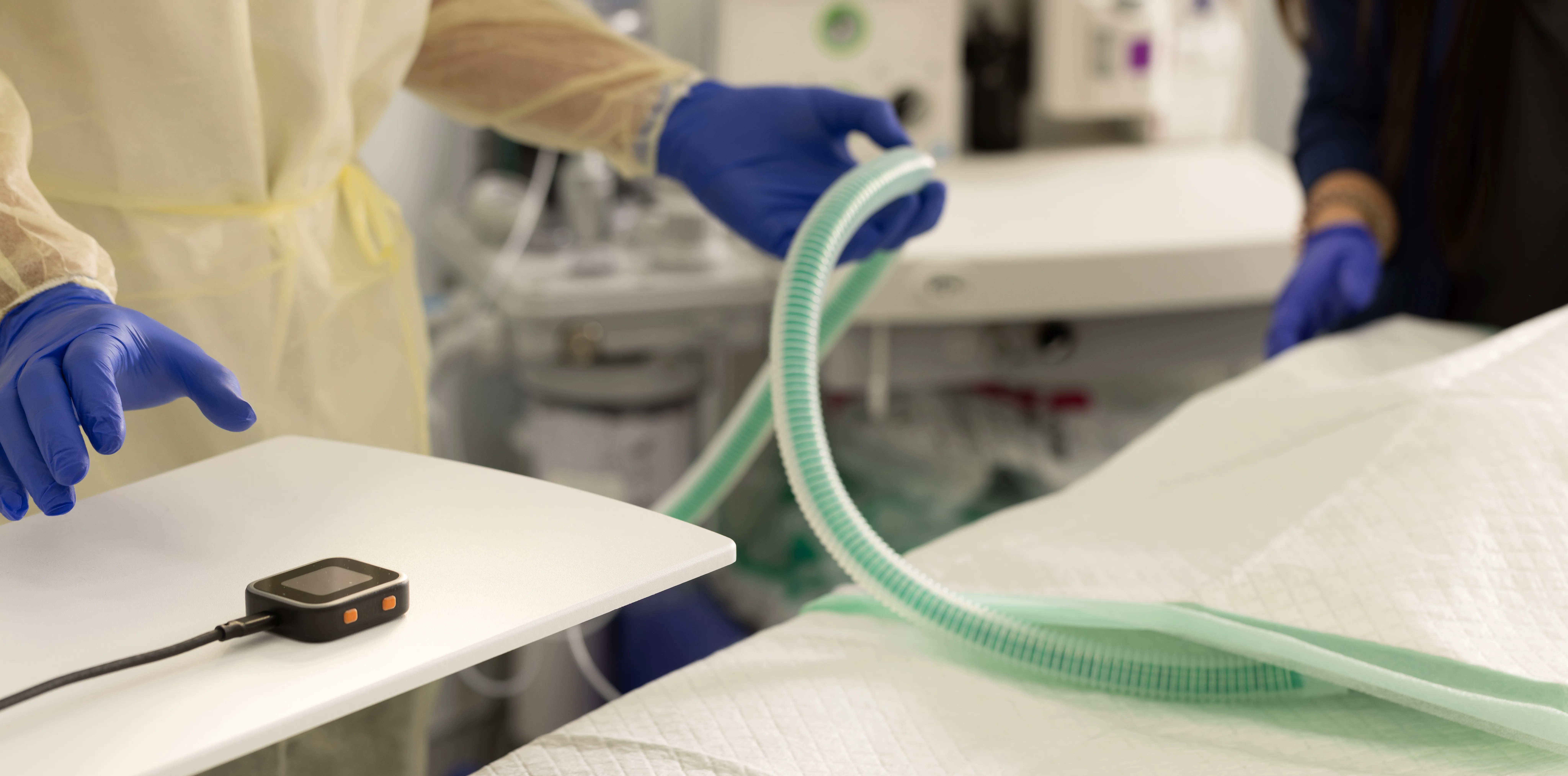 A surgeon reaches towards a SciFi headstage that is laying on a table in the operating room.