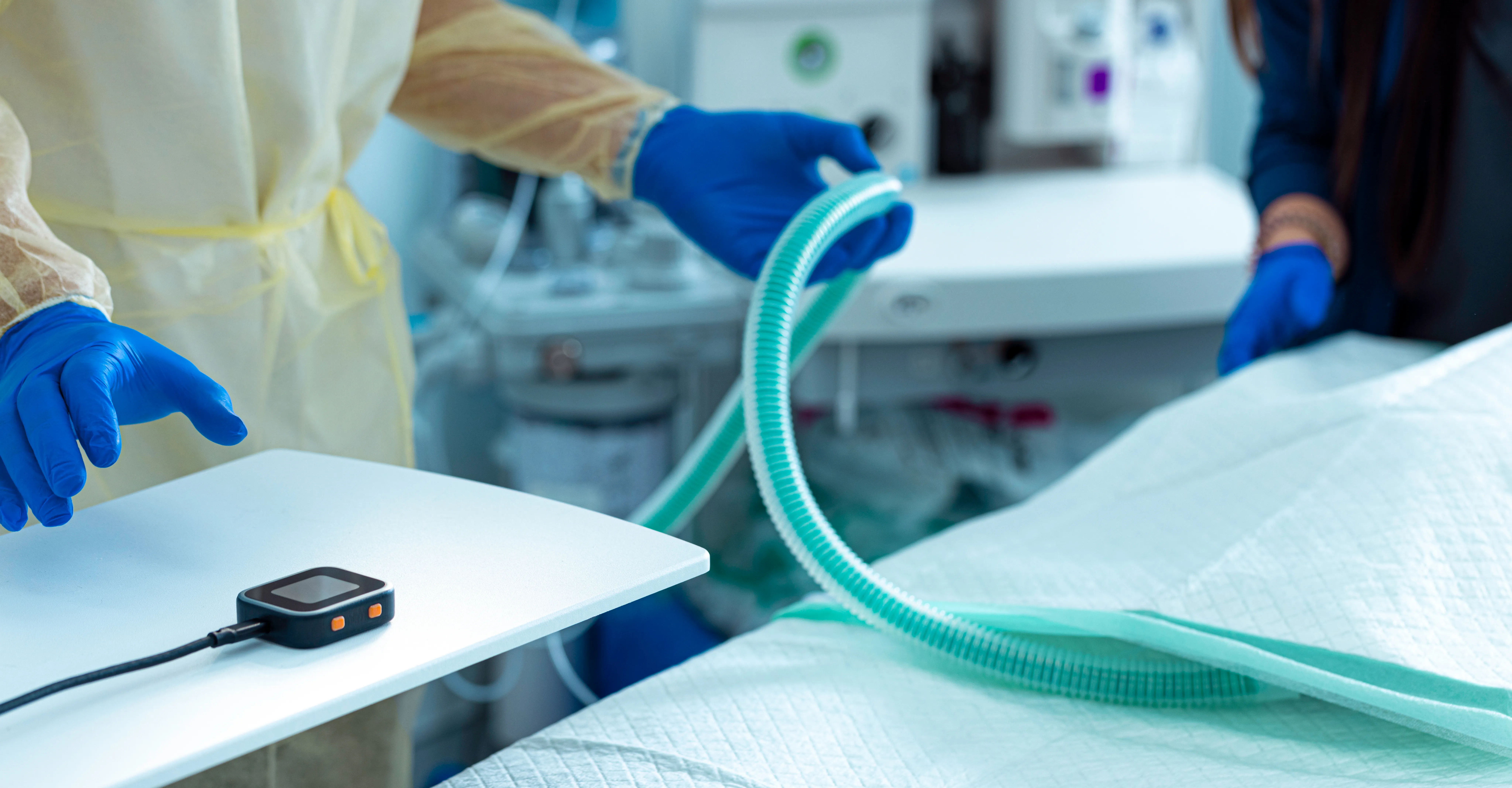 A surgeon reaches towards a SciFi headstage that is laying on a table in the operating room.