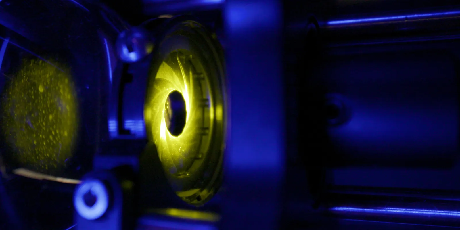 Yellow light shutters through a mechanical iris in a box dimly lit blue.